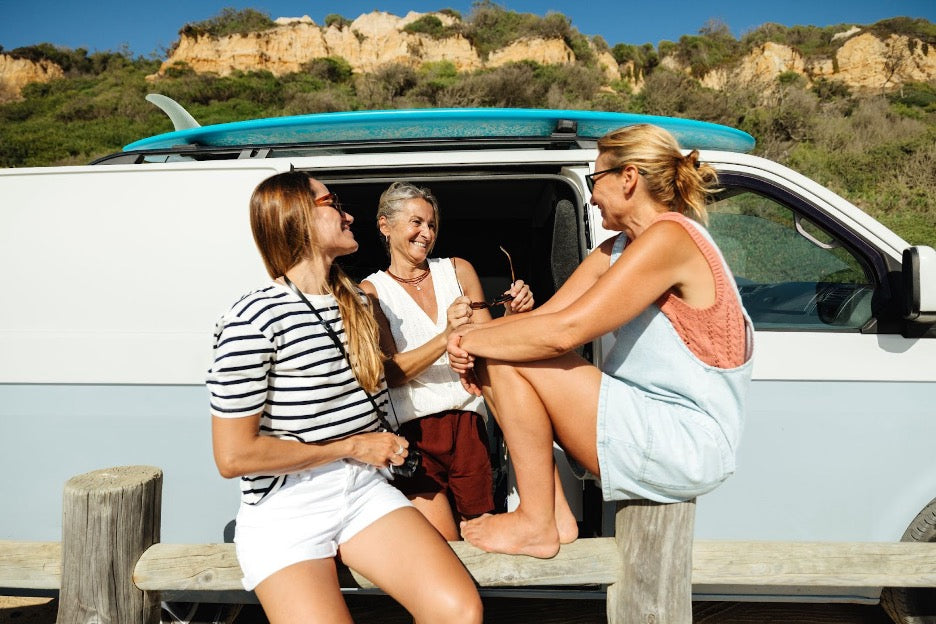 A group of relaxed people in a van on the beach.